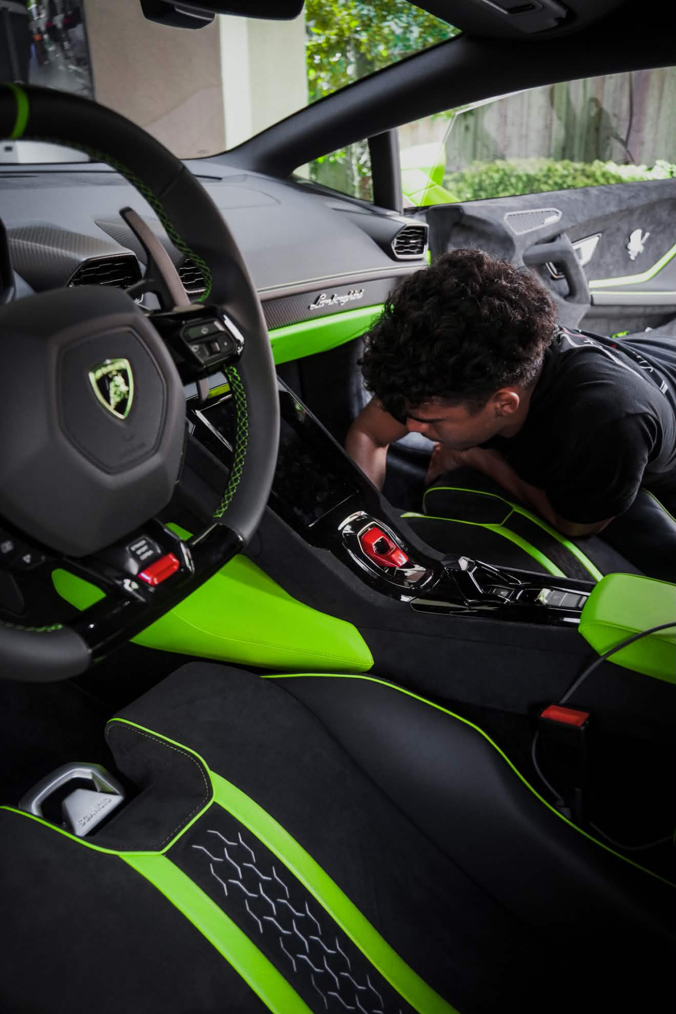 Detailer cleaning the center console of a green Lamborghini interior