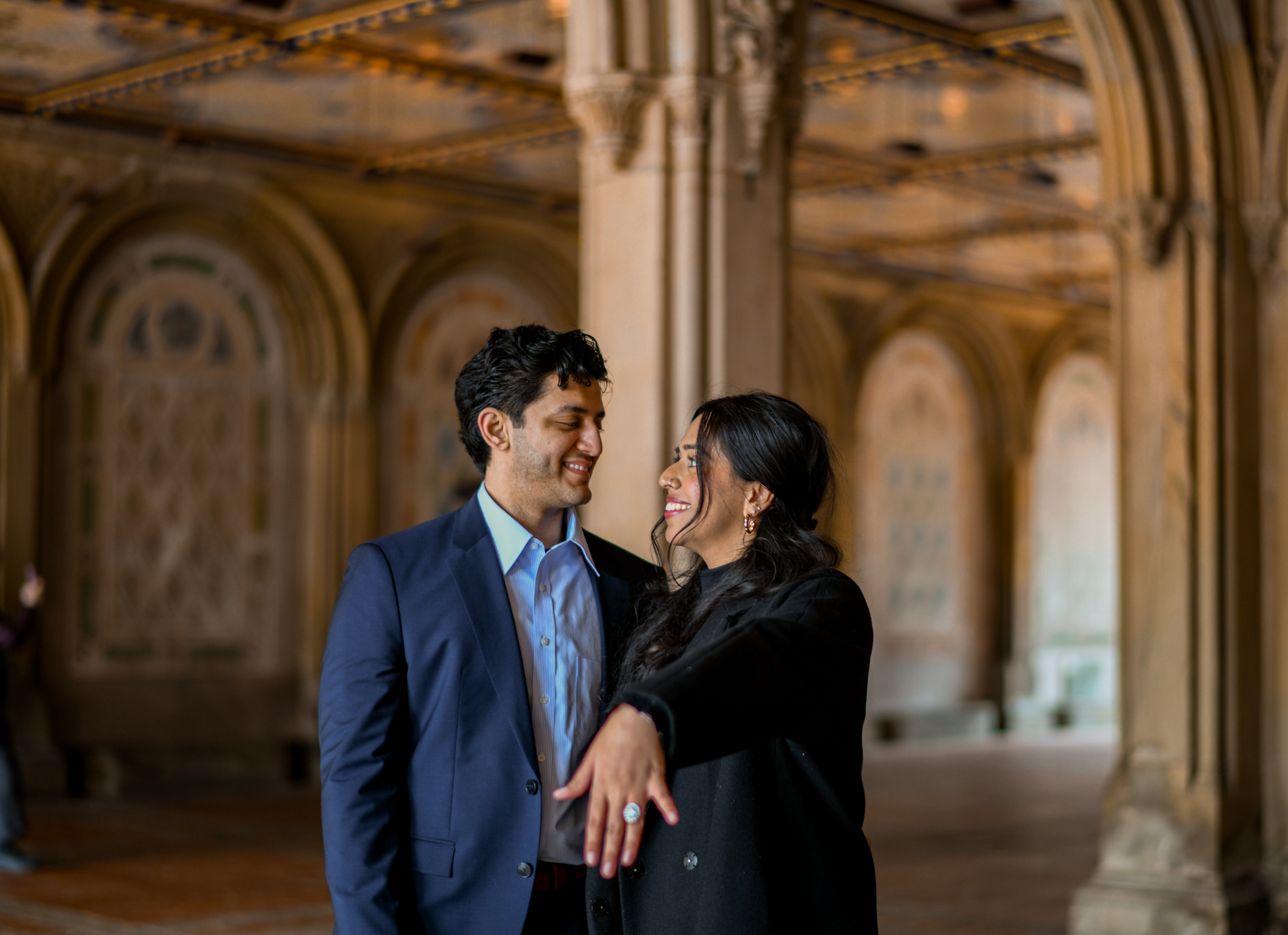 Engaged couple smiling together beneath ornate architecture