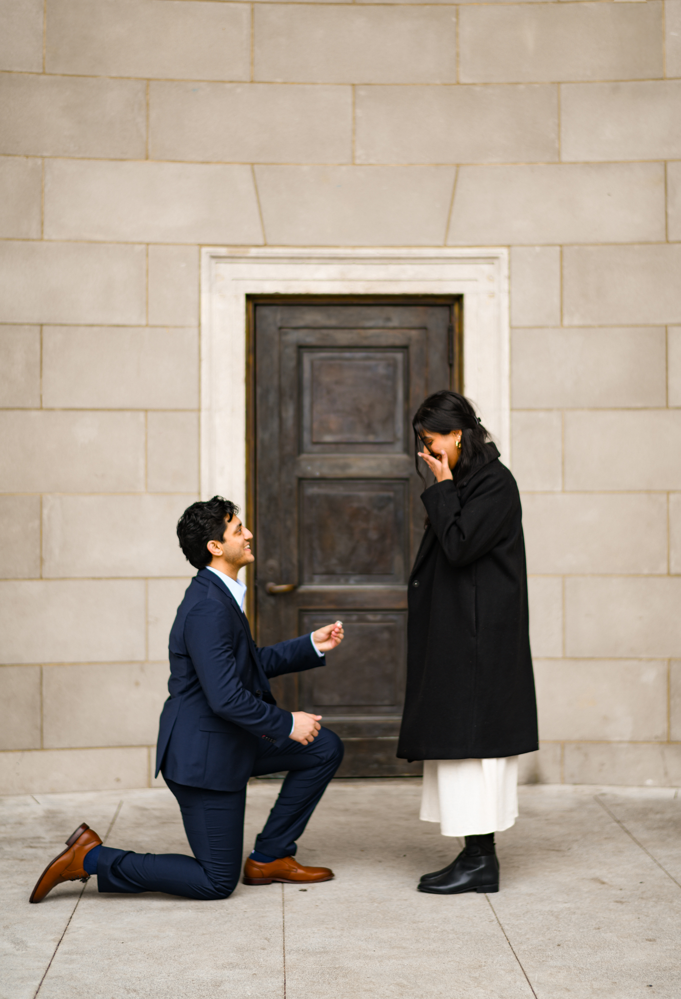 Surprised partner reacting to a proposal outside a stone building